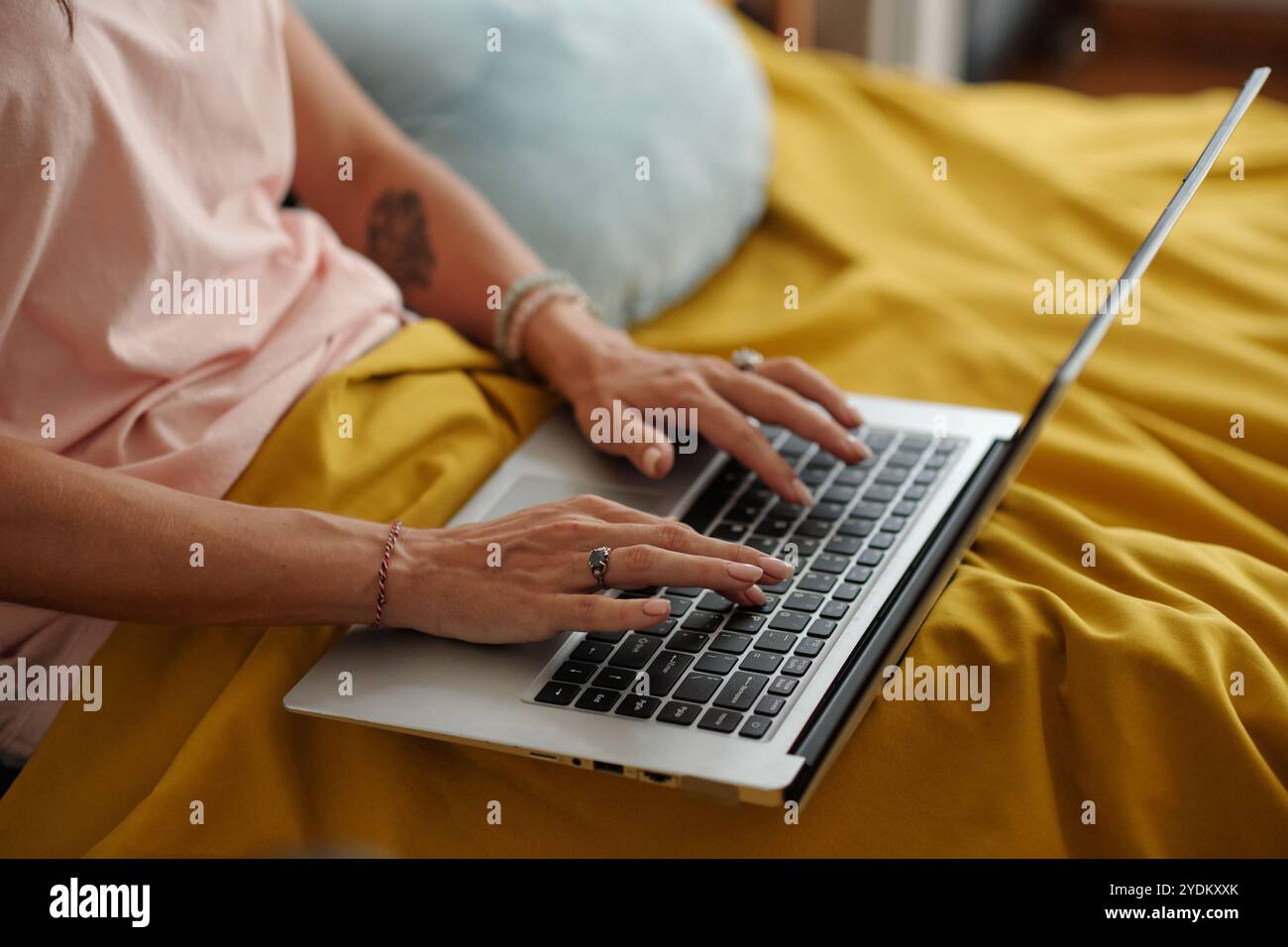 Typing on Laptop While Sitting on Yellow Blanket Stock Photo