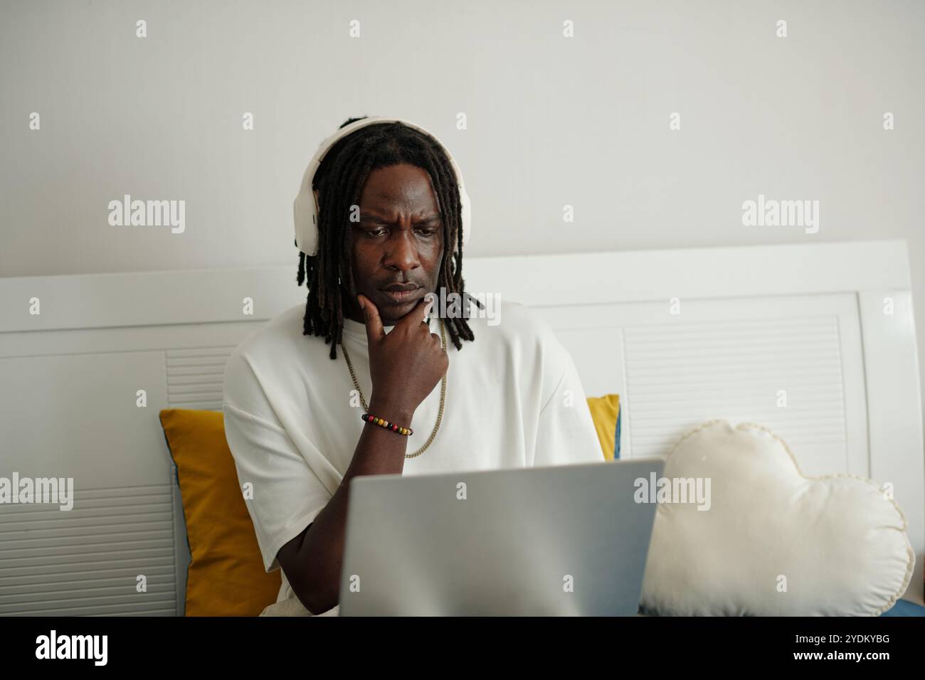 Pensive Man Wearing Headphones Using Laptop Stock Photo