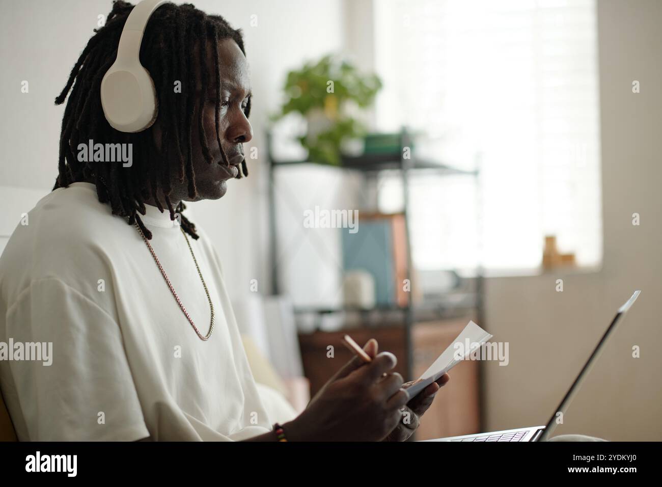 Young Man Listening to Music While Writing Notes Stock Photo