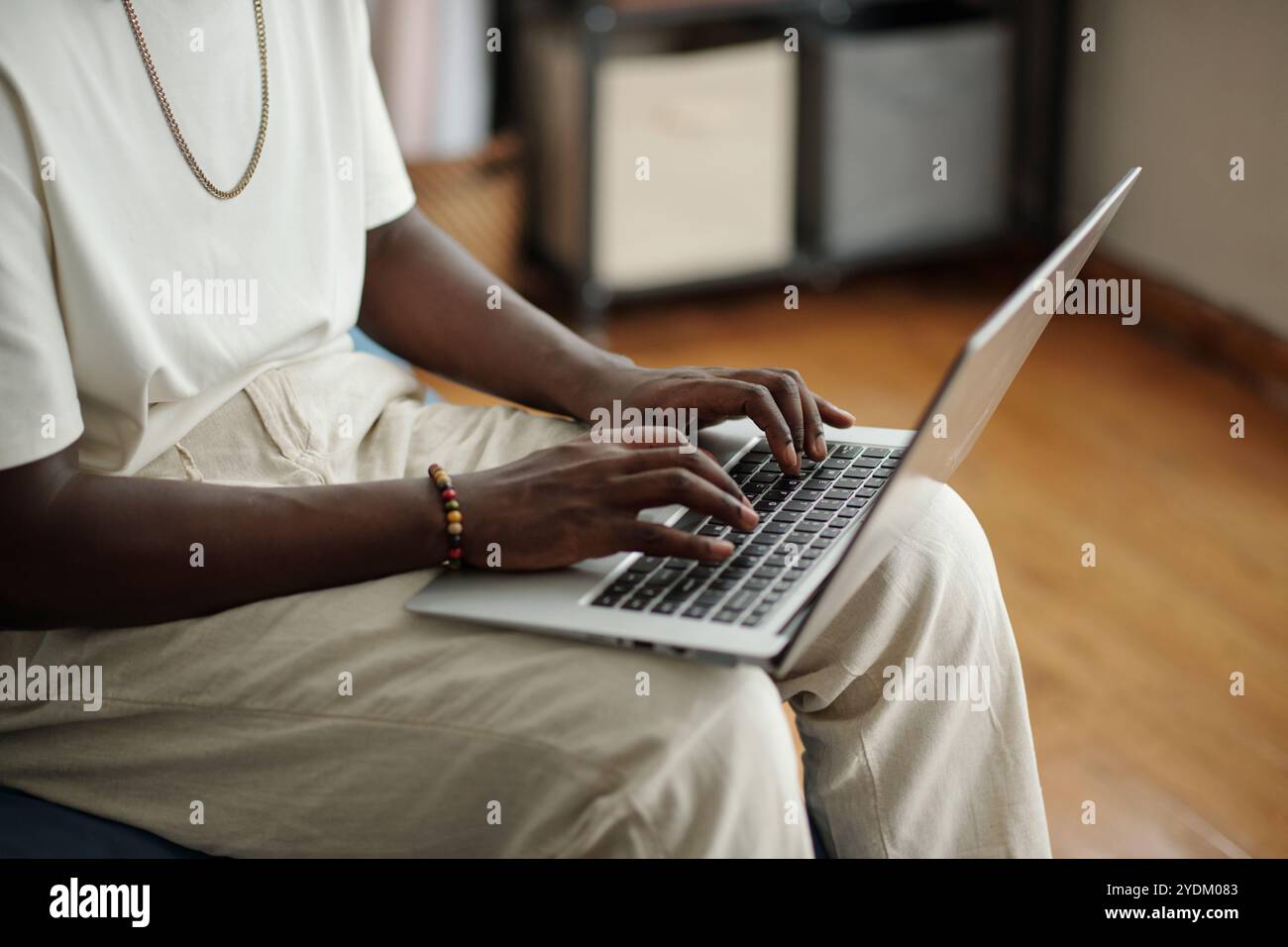 Young Man Typing on Laptop in Comfortable Setting Stock Photo