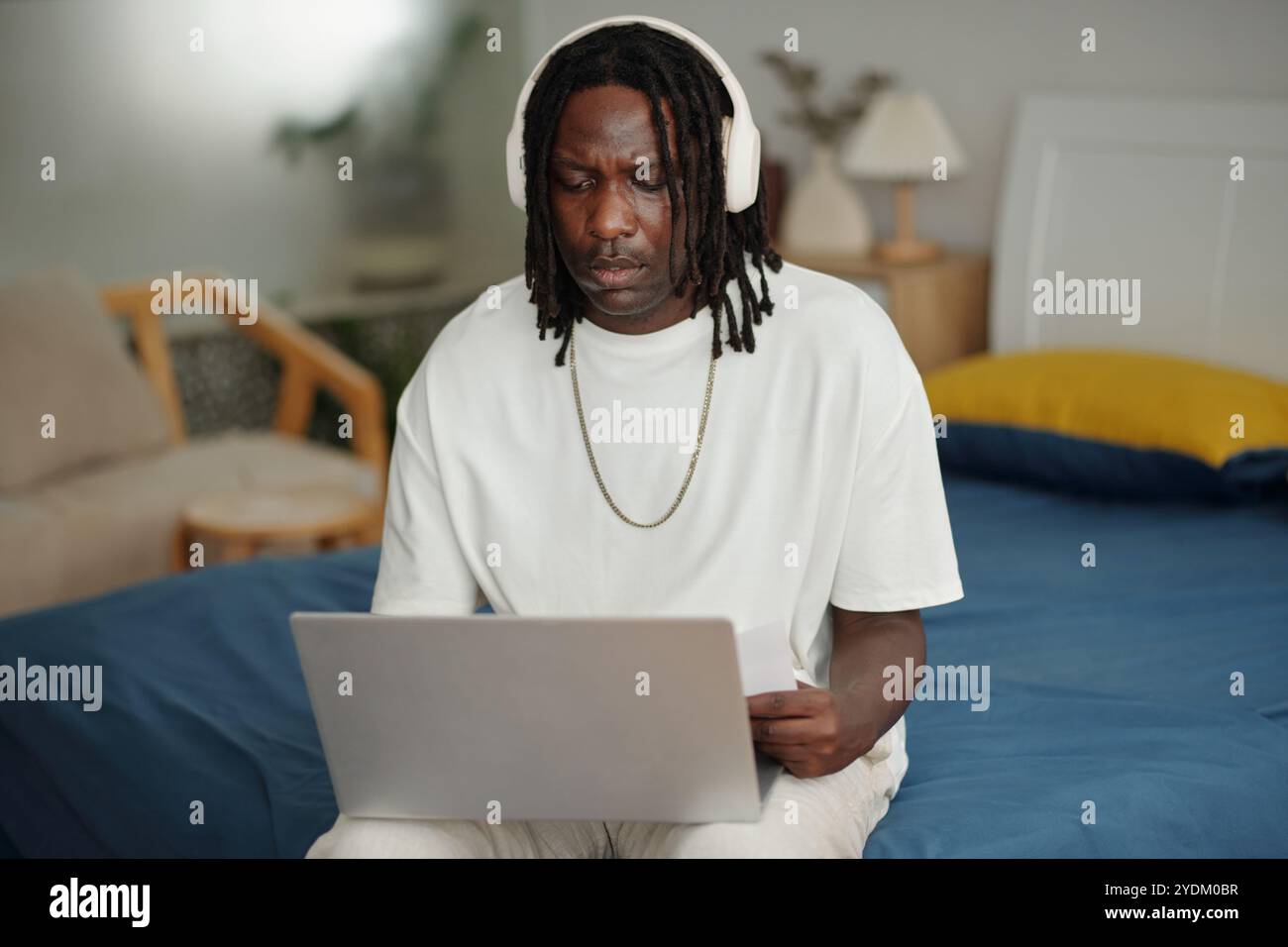 Focused Man Using Laptop at Home Office Setting Stock Photo