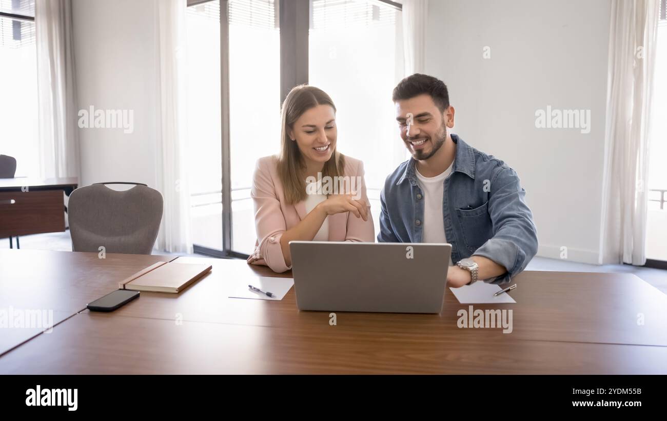 Couple of happy business workers talking at laptop Stock Photo