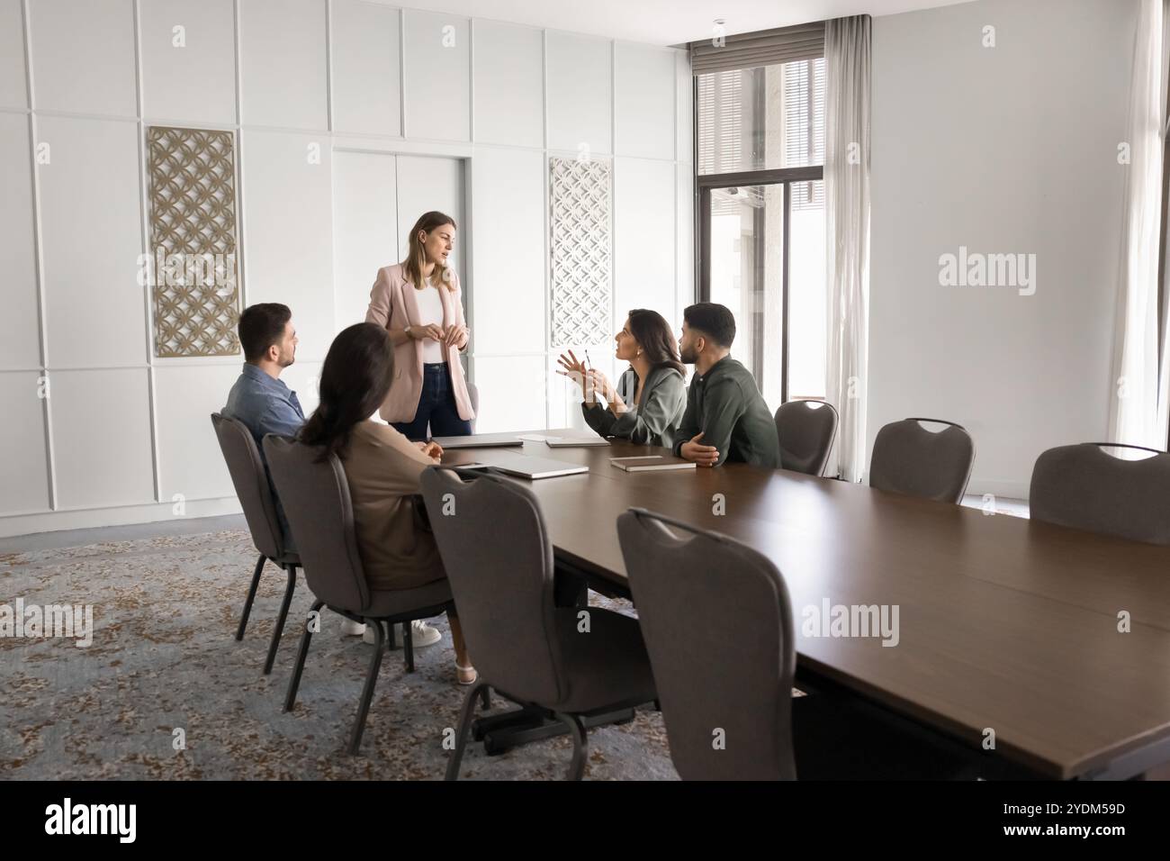 Serious female boss standing at large office meeting table Stock Photo ...