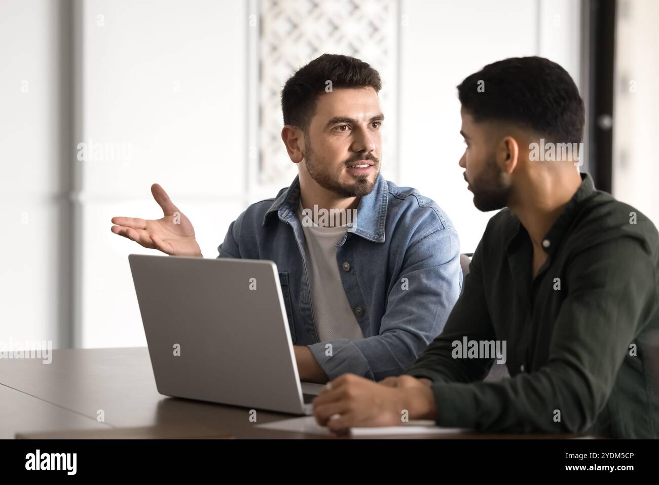 Confident young Middle Eastern startup leader man talking to partner Stock Photo