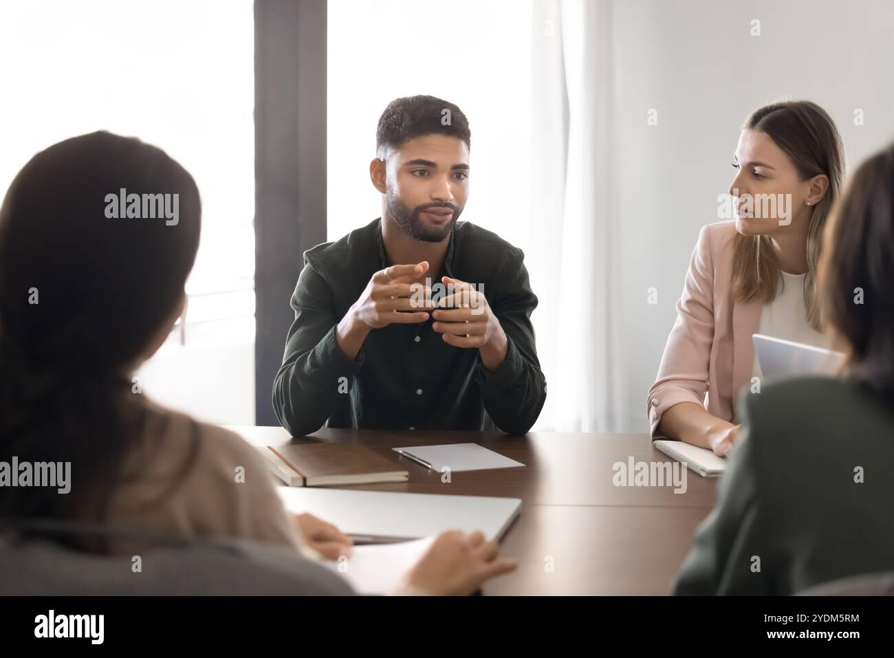 Serious young Middle Eastern project manager talking to partners Stock Photo