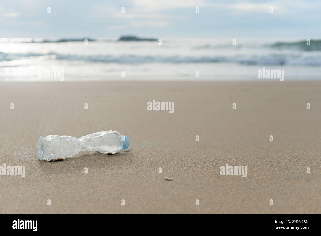 An empty plastic bottle lies on the deserted sandy beach Stock Photo