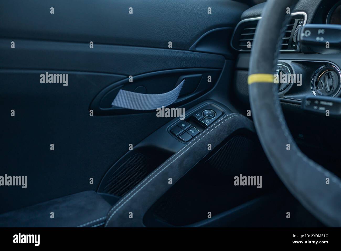 Luxury car door interior with fabric pull handle and window controls. Stock Photo