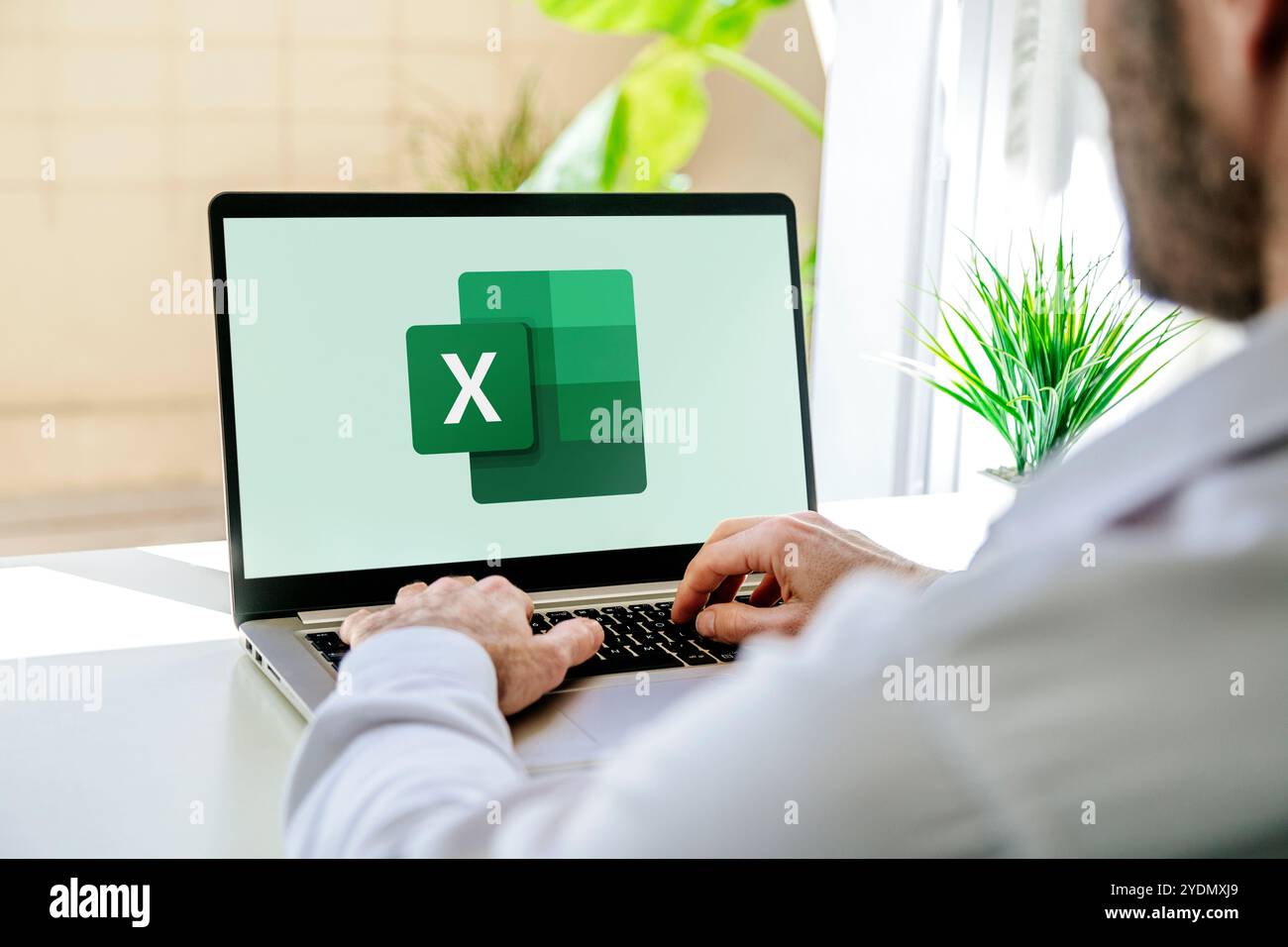 Man using a laptop computer displaying logo of Microsoft Excel on the ...