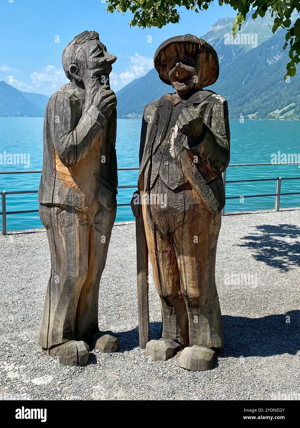 Lakeside Wooden Sculptures of Two Elderly Figures in Conversation - Smartphone Captured Stock Image