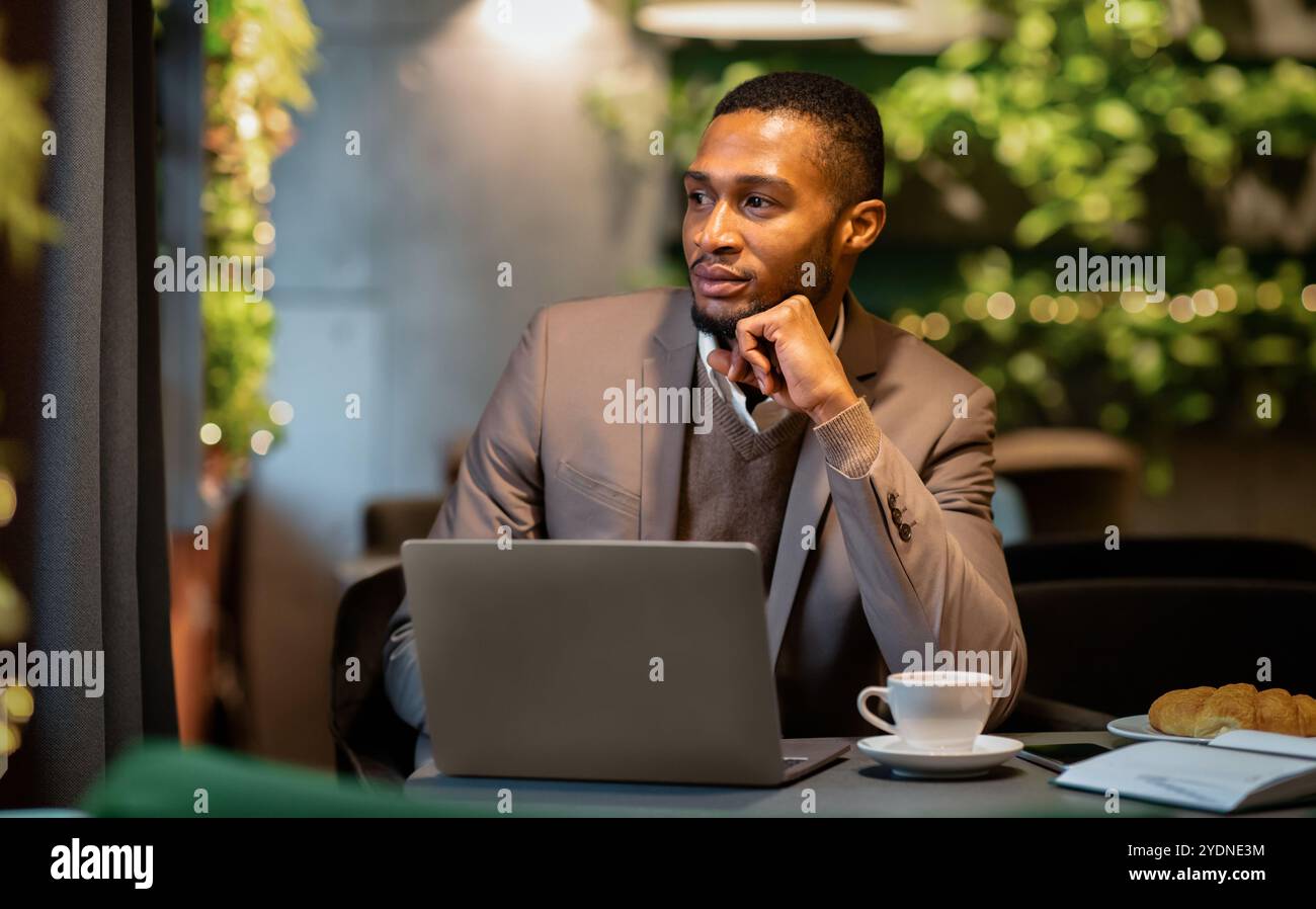 Afro manager drinking tea and using personal computer at cafe Stock Photo
