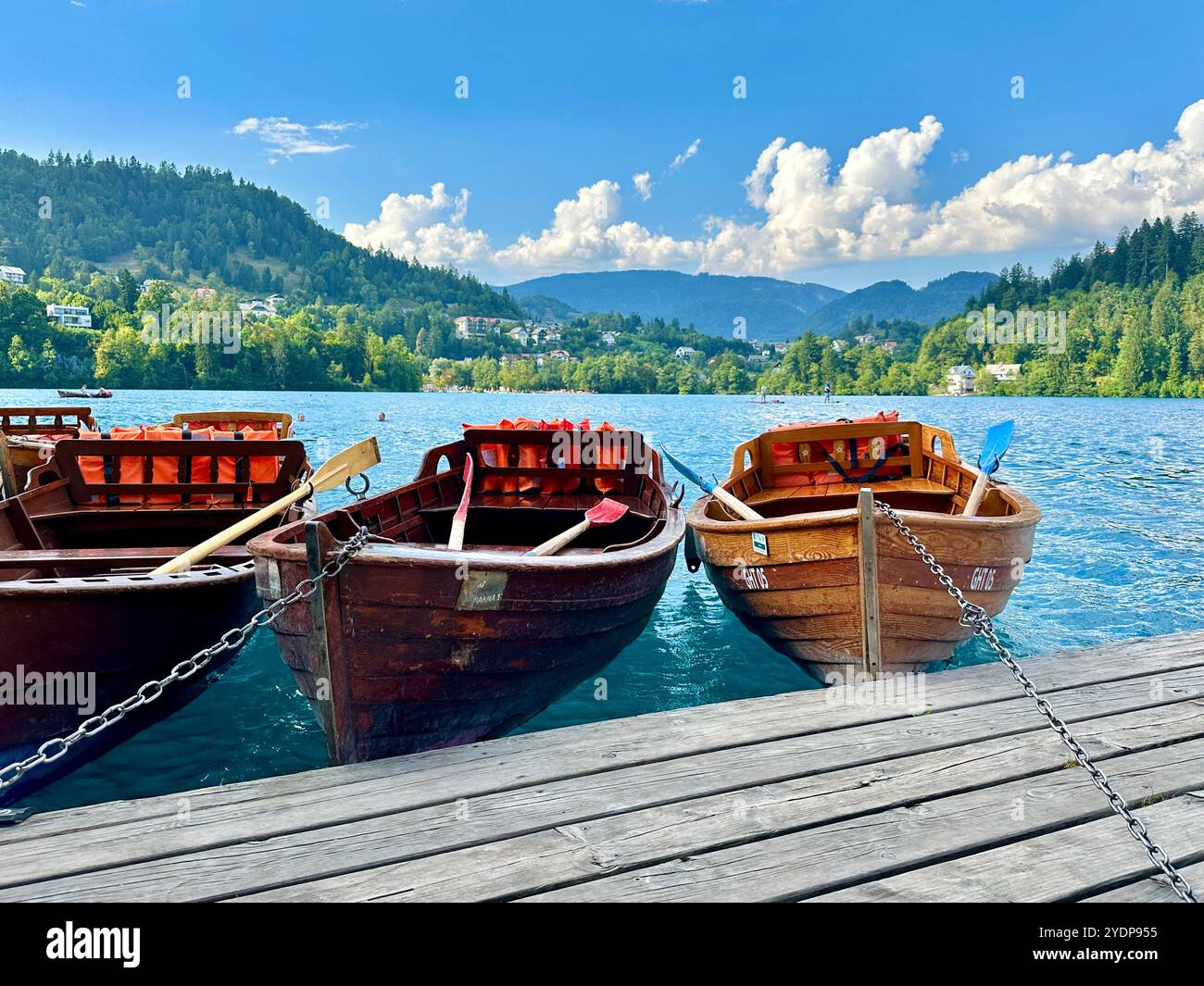 The photo beautifully captures a boat gently floating on a serene lake, surrounded by a stunning mountain landscape in Slovenia on a warm summer day. - Smartphone Captured Stock Image
