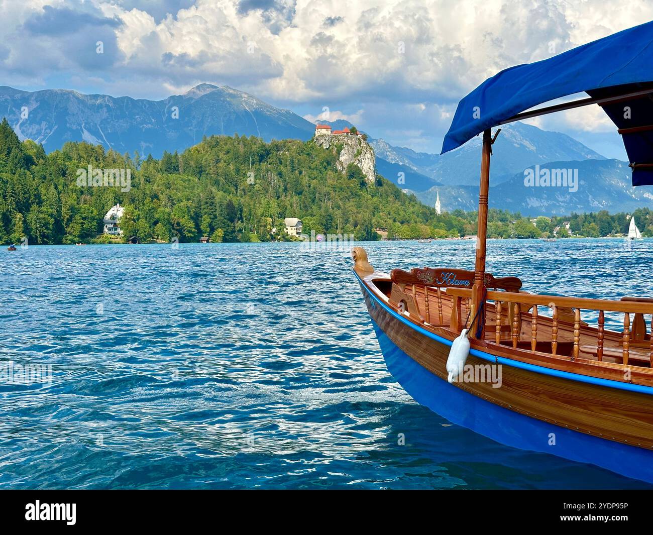 The photo beautifully captures a boat gently floating on a serene lake, surrounded by a stunning mountain landscape in Slovenia on a warm summer day. - Smartphone Captured Stock Image