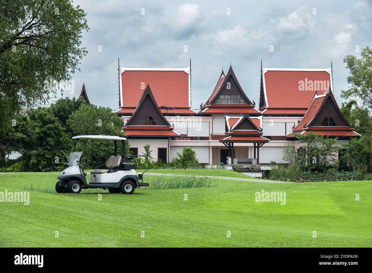 Picture of Golf buggy with green grass field with cloudy sky and big house in the ...