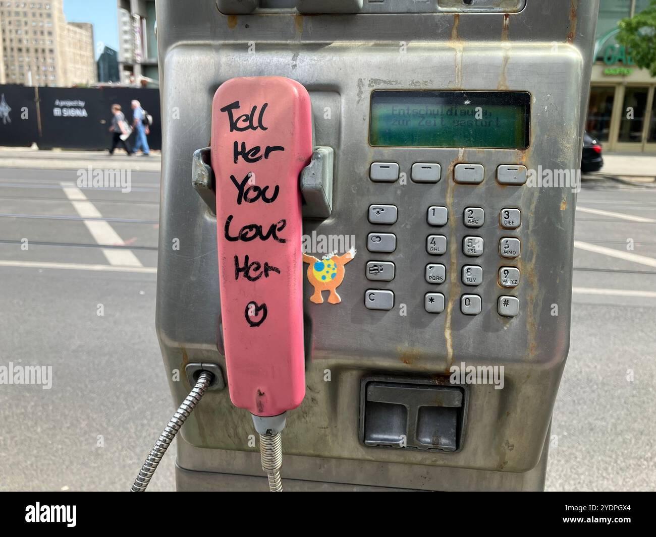 A payphone with the message 'Tell Her You Love Her' written on the pink receiver near Alexanderplatz Bahnhof. Mitte, Berlin, Germany. 22nd May 2023. - Smartphone Captured Stock Image