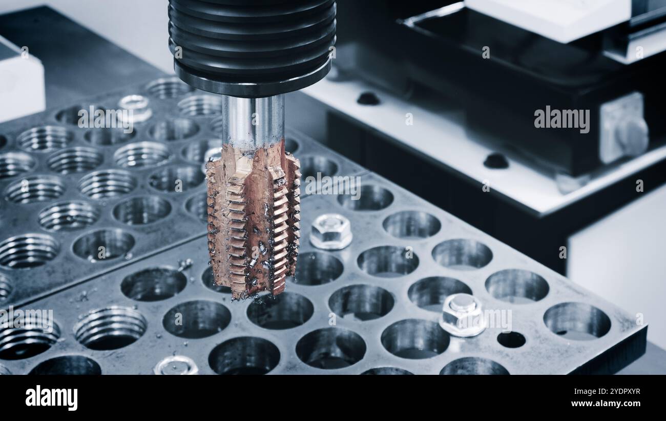 Part of a milling machine used to cut a piece of metal. The machine is surrounded by a number of small metal parts that it cuts. The concept of indust Stock Photo