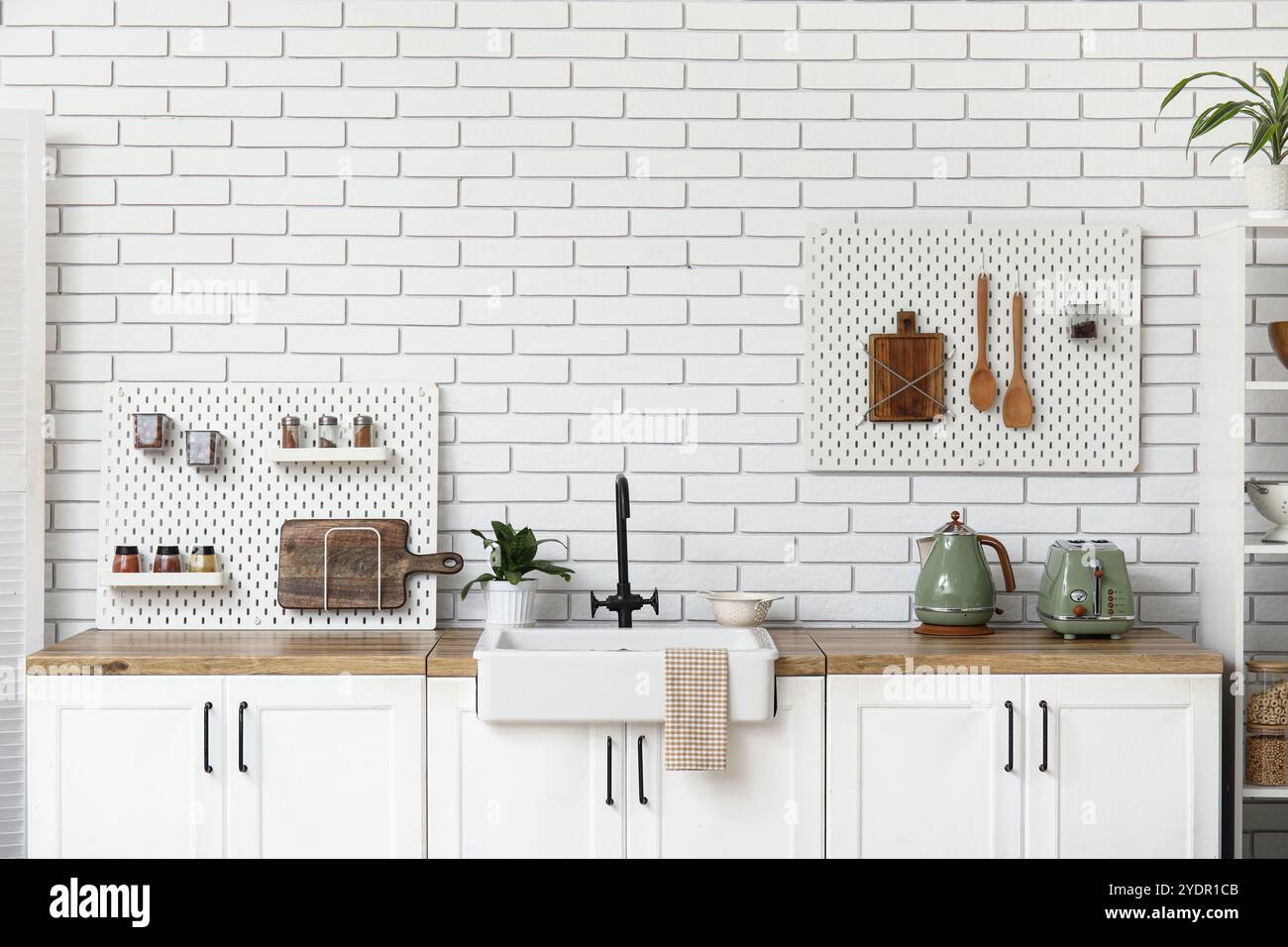 Stylish light kitchen with pegboards and kitchenware Stock Photo