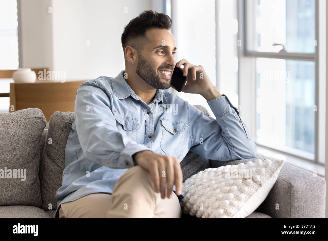 Dreamy happy handsome Hispanic freelancer man talking on cellphone Stock Photo