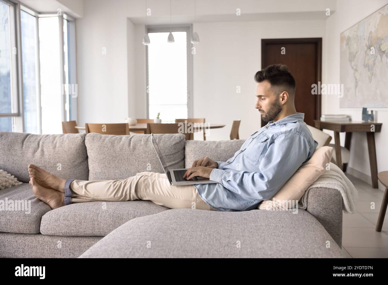 Focused relaxed young Hispanic man resting on comfortable sofa Stock Photo