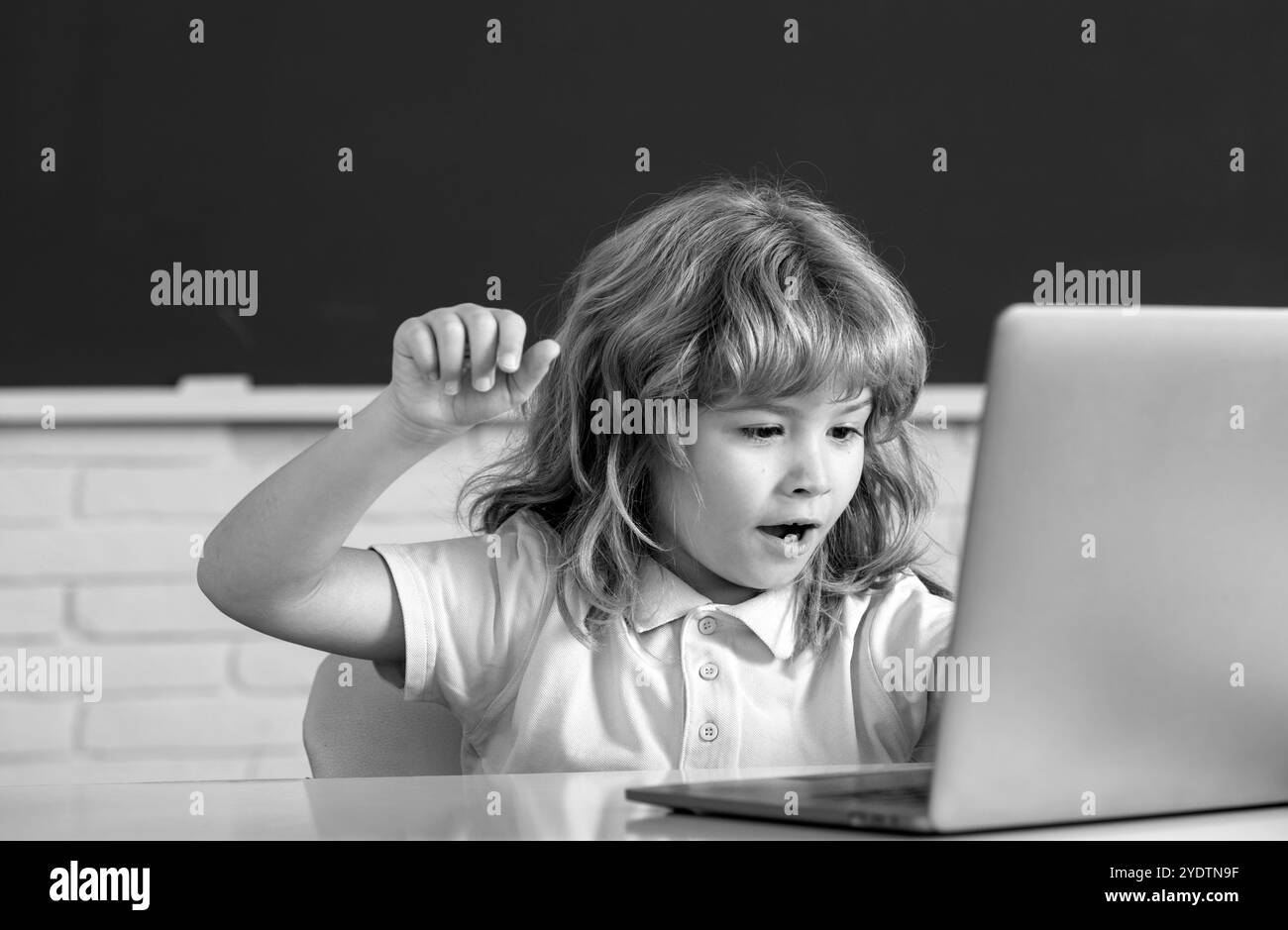 School child using digital pc laptop in class. Portrait of funny pupil of primary school study programming. Online learning technology, virtual Stock Photo