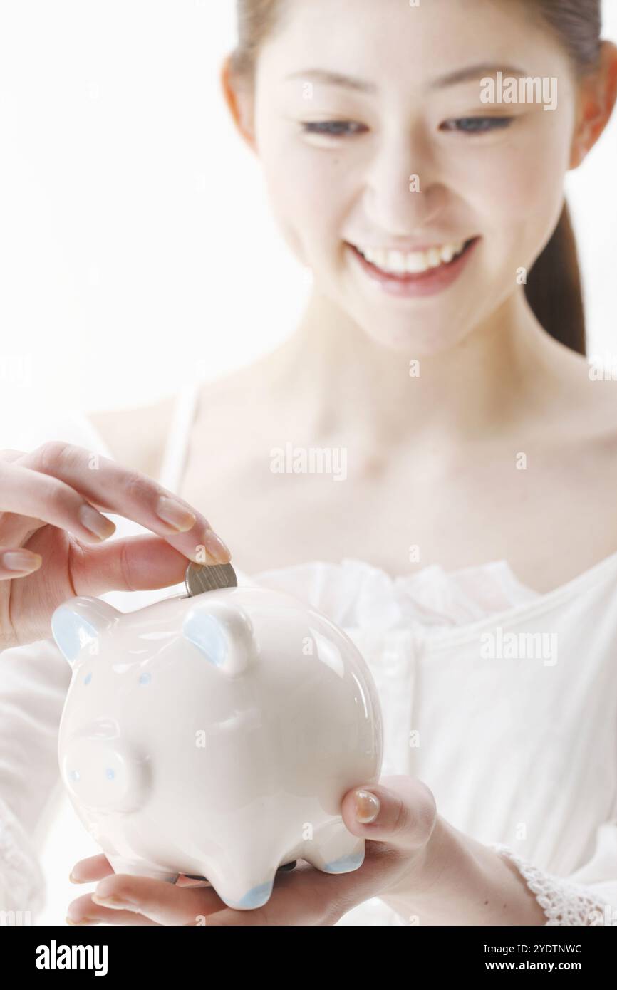 Woman putting money into piggy bank Stock Photo - Alamy