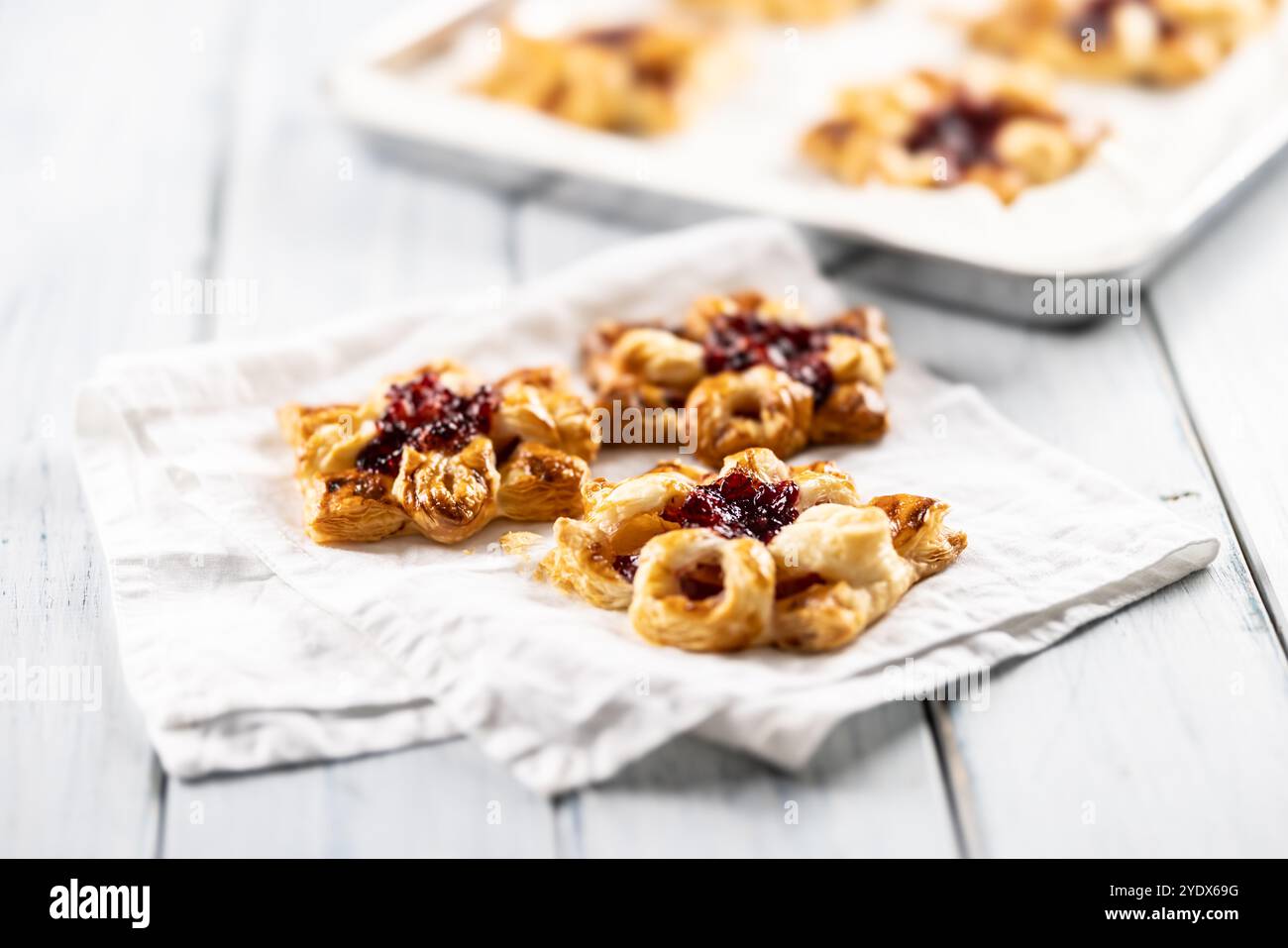 Sweet dessert pastries made of puff pastry with strawberry jam filled with caramelized apple. Stock Photo