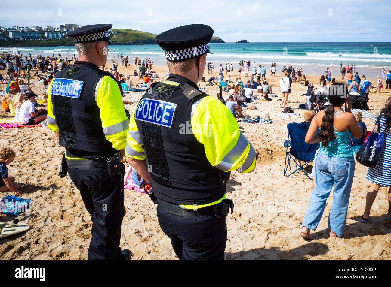 Two constables of the Devon & Cornwall police force patrolling amongst holidaymakers enjoying themselves on Fistral Beach in Newquay in Cornwall in th Stock Photo