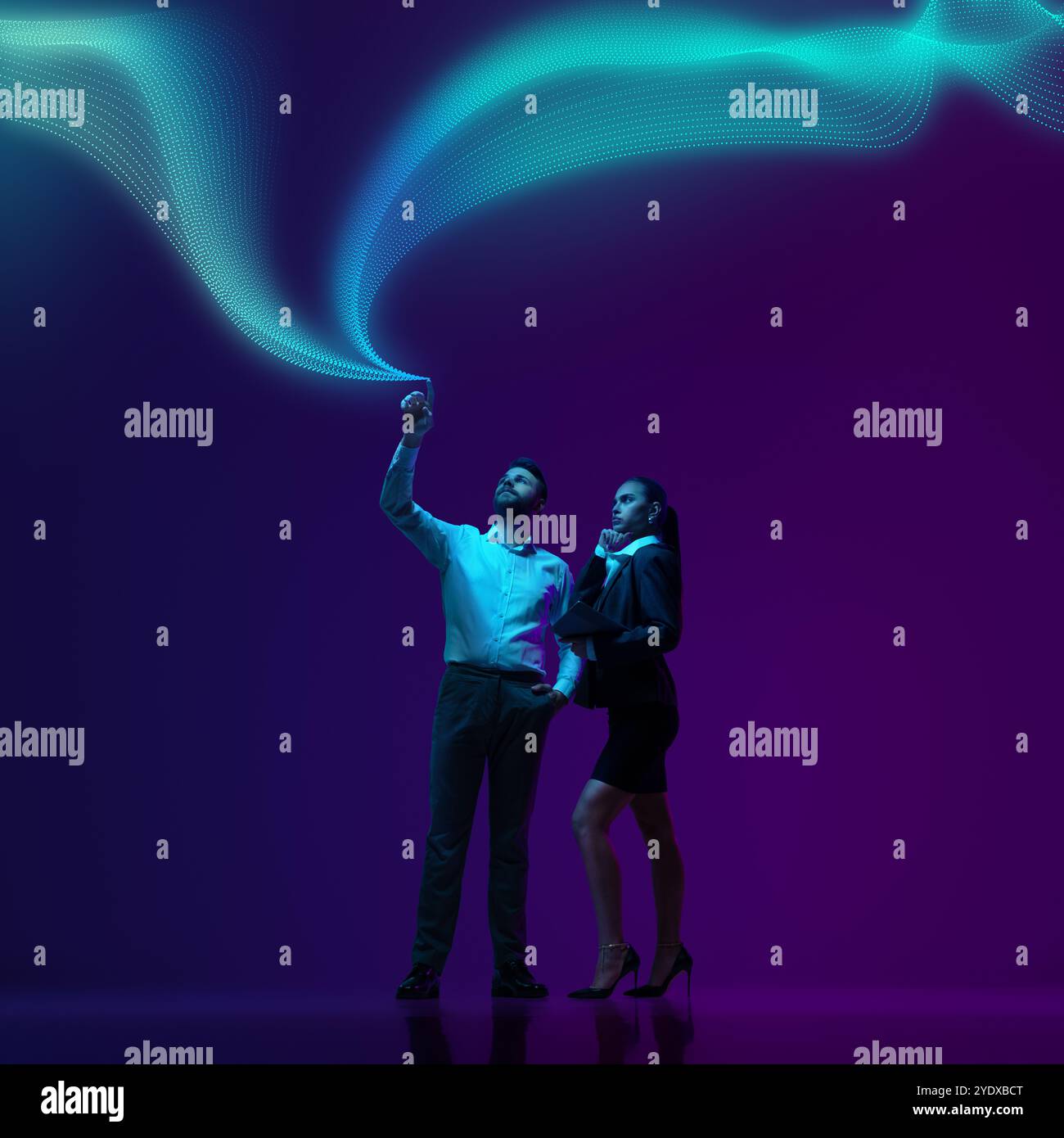 Man and his assistant in formal suits, interacts with flowing waves of digital data, symbolizing leadership in age of technology Stock Photo
