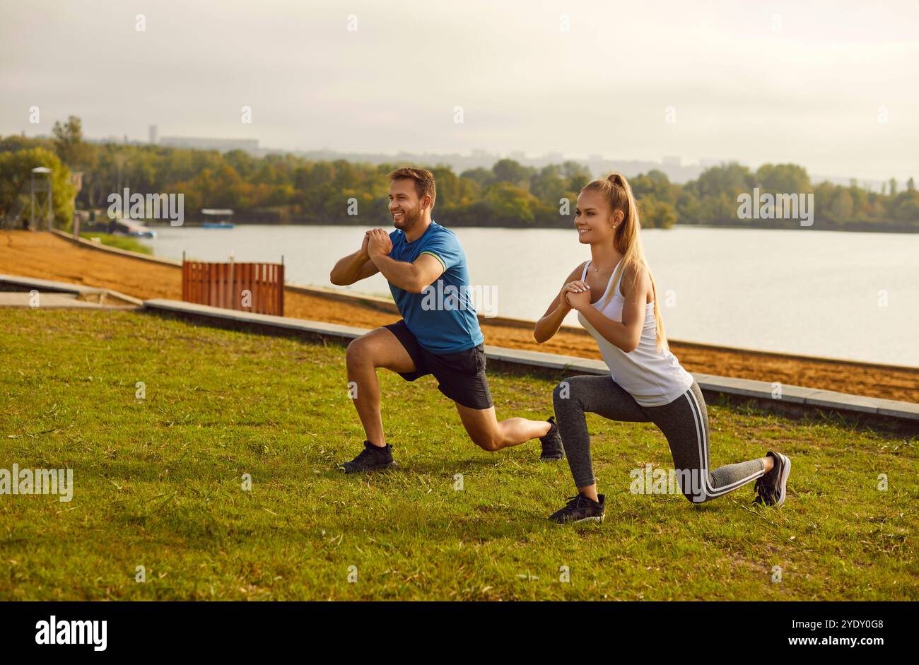 Active sporty young couple man and woman doing stretching exercising in nature. Stock Photo