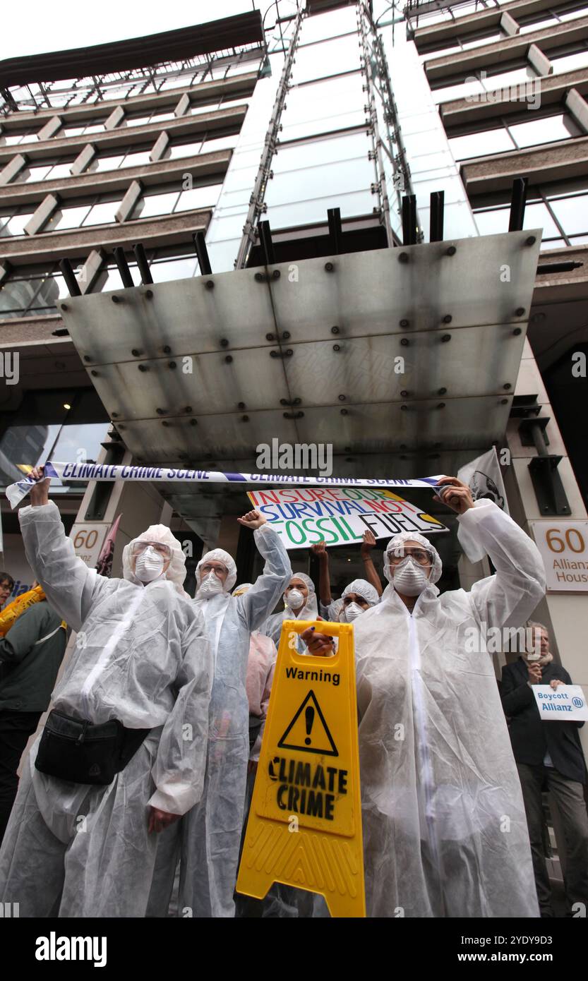 London, England, UK. 28th Oct, 2024. Protesters in Hazmat suits, masks and with crime scene tape protest outside the Allianz insurance company offices. Extinction Rebellion (XR) walk around the City of London and stop and demonstrate outside the offices of insurance companies that are continuing to insure fossil fuel companies despite the warnings of a climate crisis from scientists. The protesters believe if the insurance companies stopped their involvement with these companies they would struggle to continue to mine. The action is the first of a week long protest directed specifically at t Stock Photo