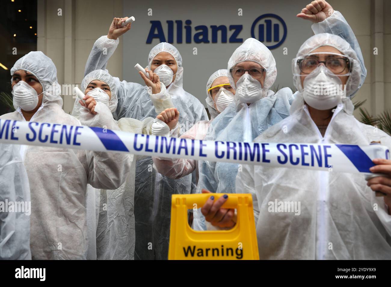 London, England, UK. 28th Oct, 2024. Protesters in Hazmat suits, masks and with crime scene tape protest outside the Allianz insurance company offices. Extinction Rebellion (XR) walk around the City of London and stop and demonstrate outside the offices of insurance companies that are continuing to insure fossil fuel companies despite the warnings of a climate crisis from scientists. The protesters believe if the insurance companies stopped their involvement with these companies they would struggle to continue to mine. The action is the first of a week long protest directed specifically at t Stock Photo