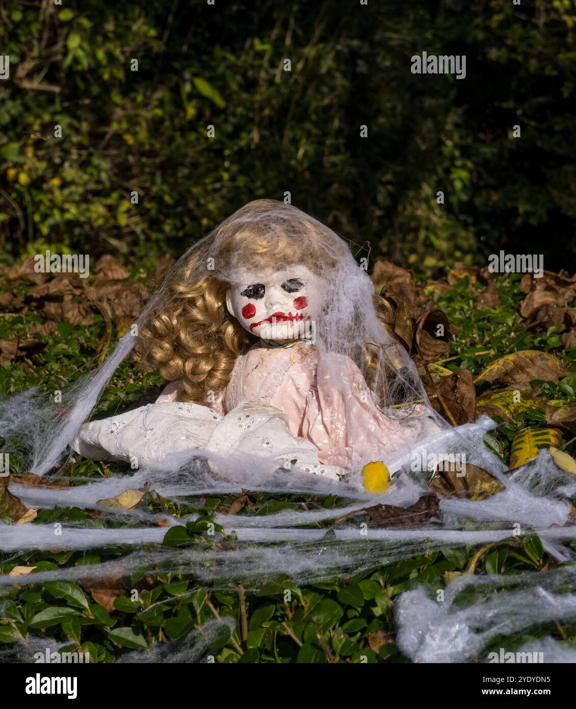 Scary Halloween doll with red mouth in hedgerow Stock Photo