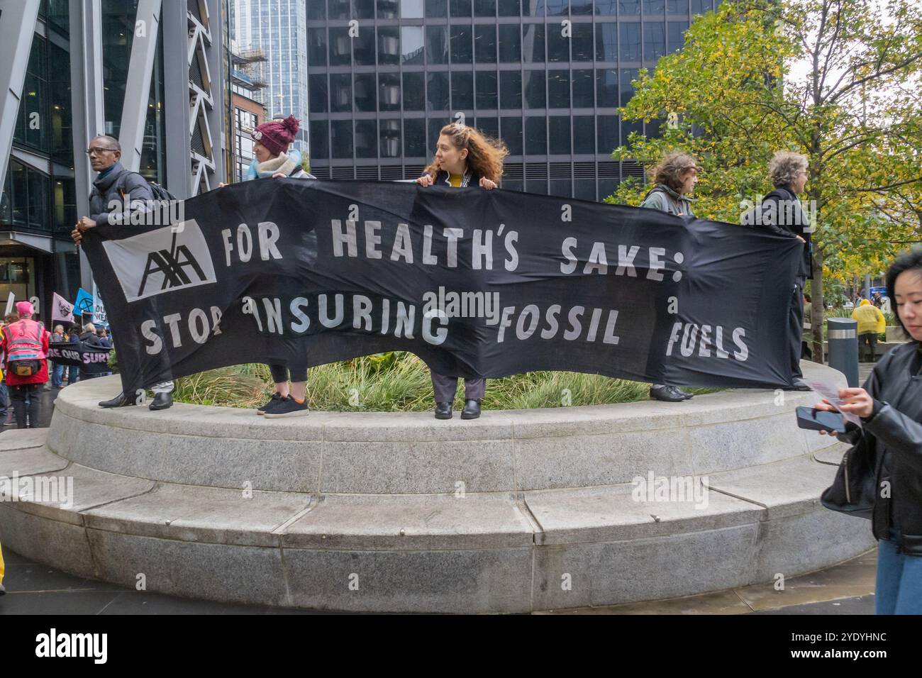 London, UK. 28 Oct 2024. AXA FOR HEALTH'S SAKE STOP INSURING FOSSIL FUELS. Extinction Rebellion marches to stages theatrical flooding scenes outside insurers in the city to show how insurers are green-lighting fossil fuel crooks to flood our homes and our lands. They hope to stop insurance for new fossil fuel projects; flooding due to global warming is already common and threatens us all. Peter Marshall/Alamy Live News Stock Photo