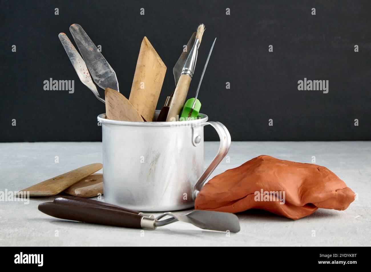 tools for modeling and sculpting and pieces of clay and plasticine on a stone table in a sculptor's workshop against a black wall Stock Photo