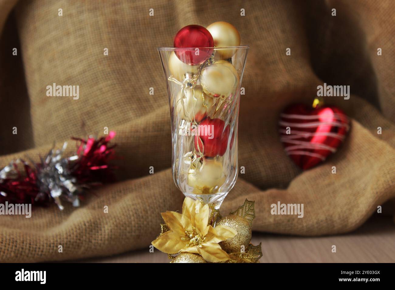 Crystal cup, champagne goblet filled with red and golden Christmas balls. Sophisticated Xmas decoration for winter season december holiday celebration Stock Photo