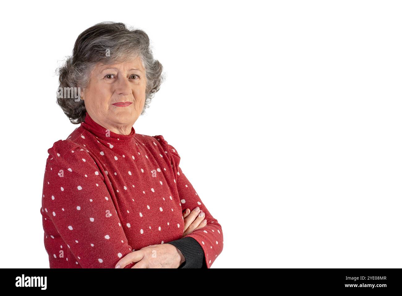 60 year old woman with crossed arms red sweater with polka dots gray hair white background Stock Photo