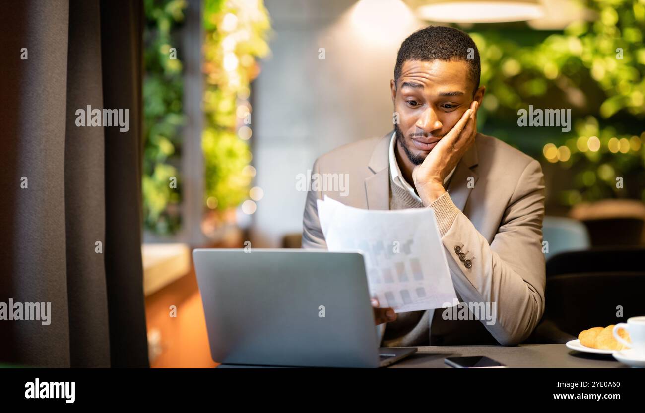 Afro businessman looking at documents with graphs Stock Photo