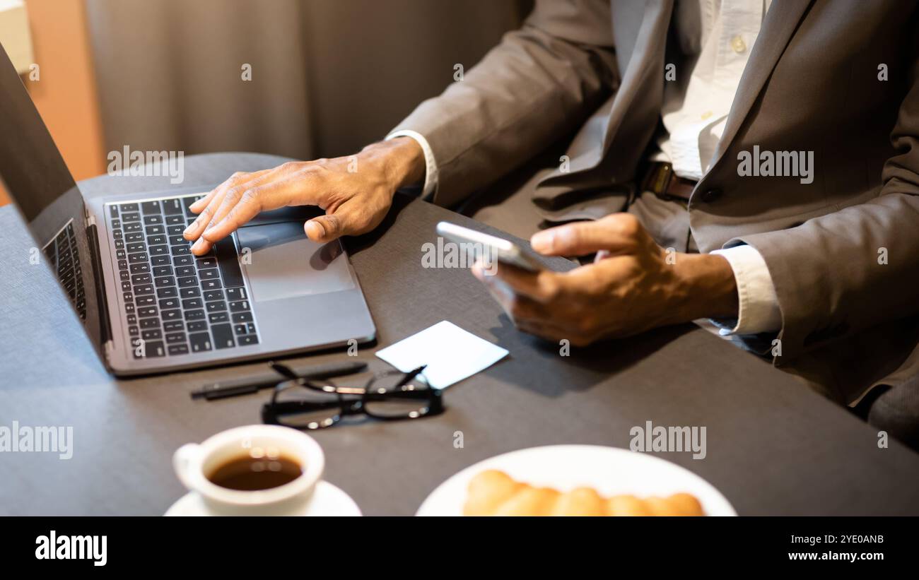Cropped image of afro guy using phone and computer Stock Photo