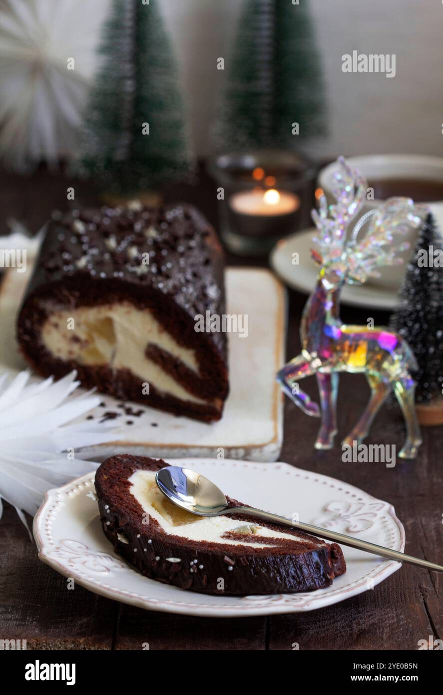 Chocolate roll stuffed with butter cream and pineapple on a Christmas background. Rustic style, selective focus. Stock Photo