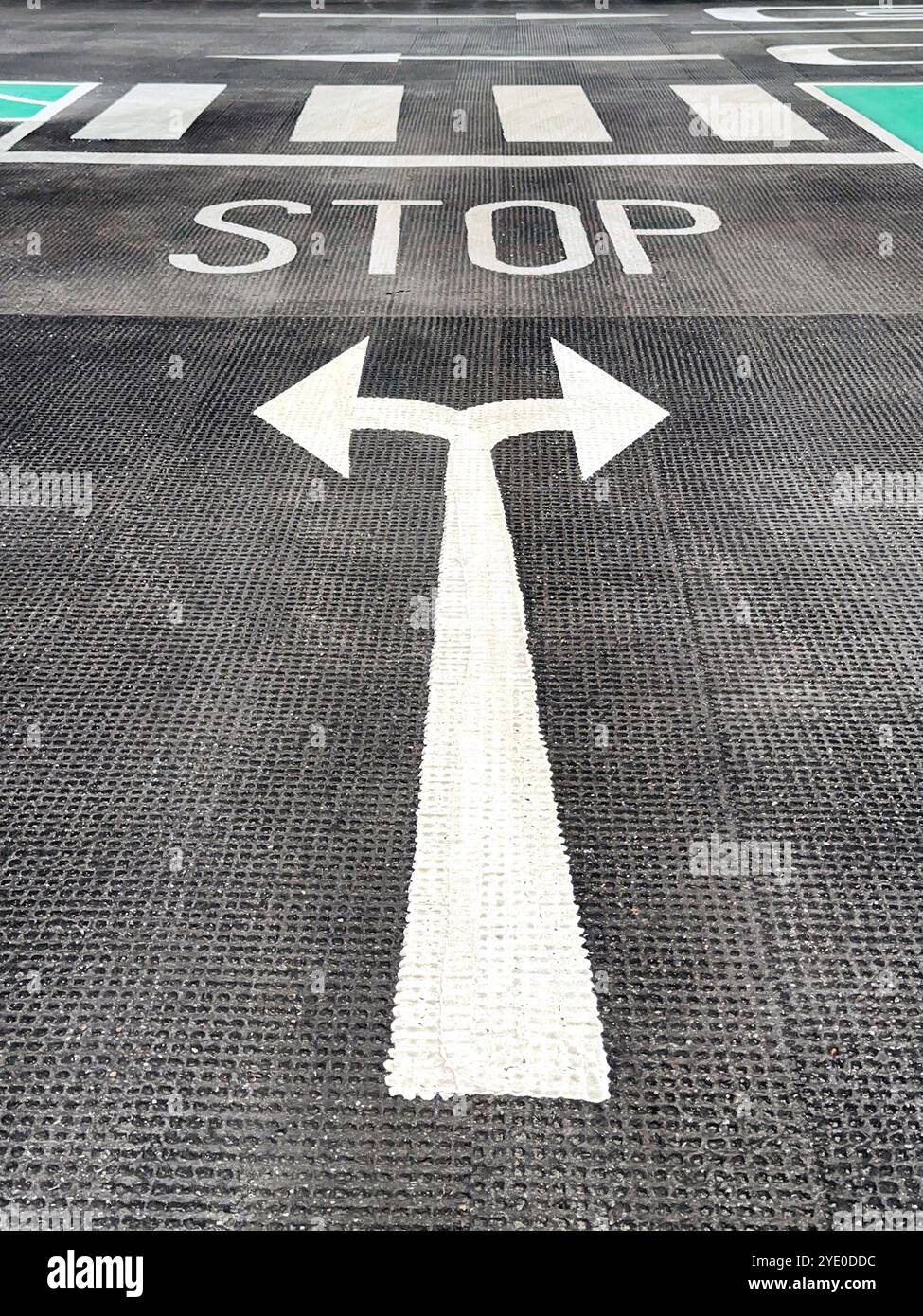 Road markings with arrows and a stop sign on the floor of a car park. No people. - Smartphone Captured Stock Image