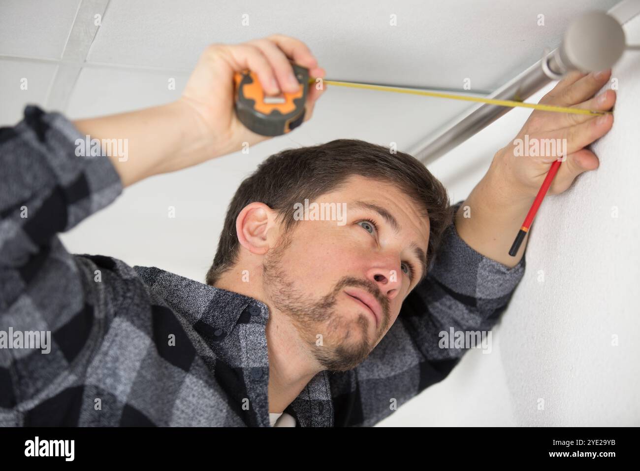 man installing curtain rail above window Stock Photo