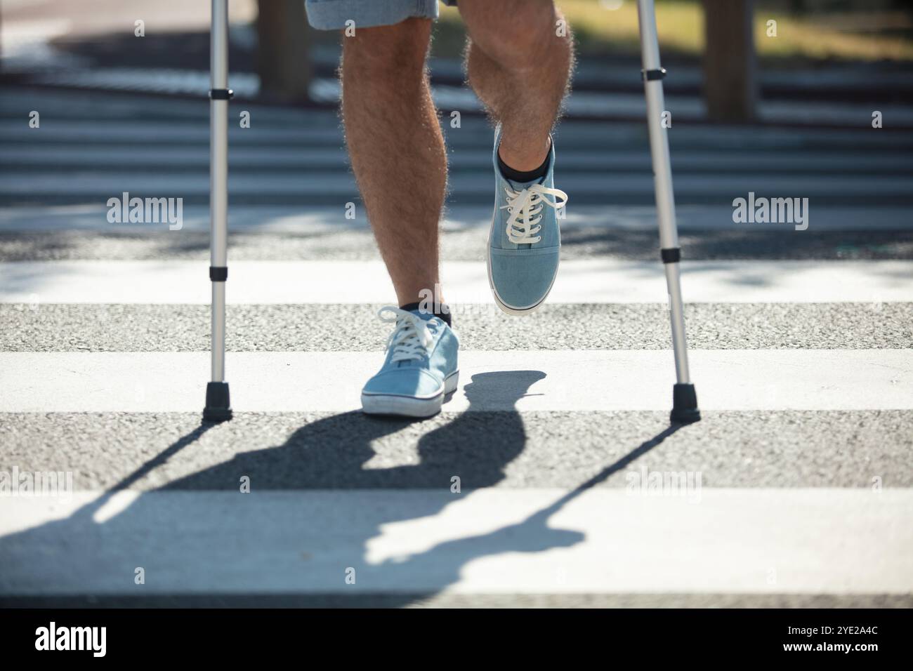 man trying to walk on street with the help crutches Stock Photo