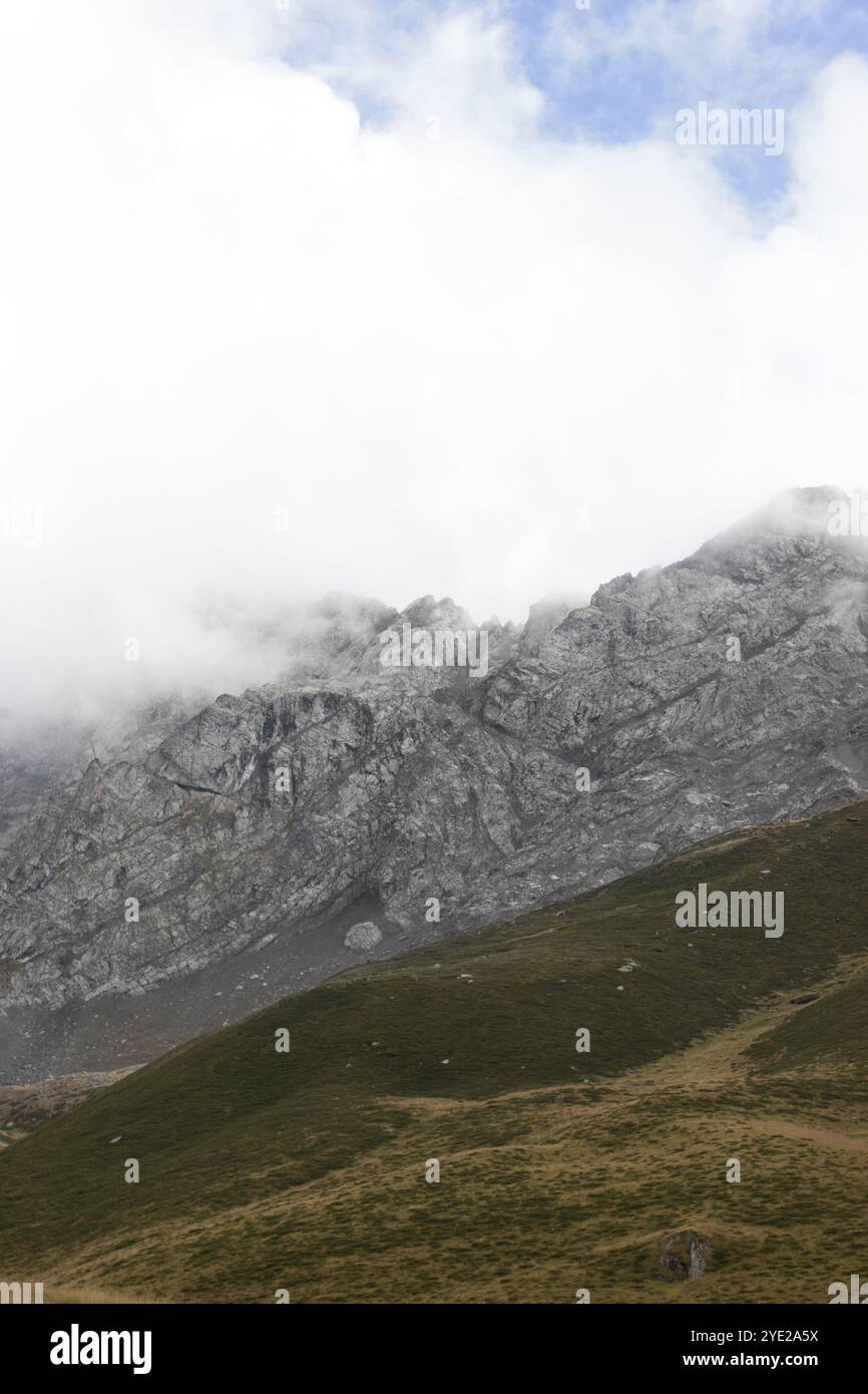 a tranquil autumn scene in the mountains of Georgia. The rugged, rocky slopes of the mountain rise into the cloudy sky, partially hidden by thick mist Stock Photo