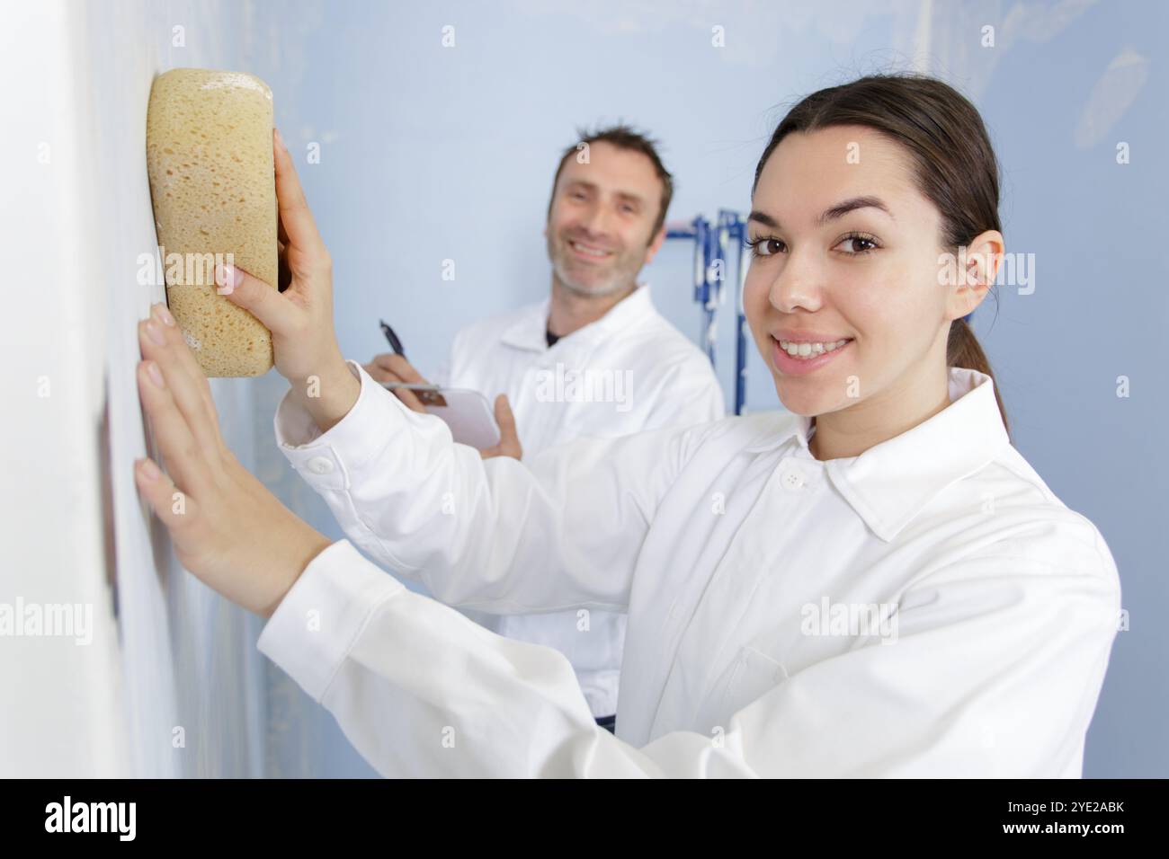 female construction worker smoothing wall surface Stock Photo