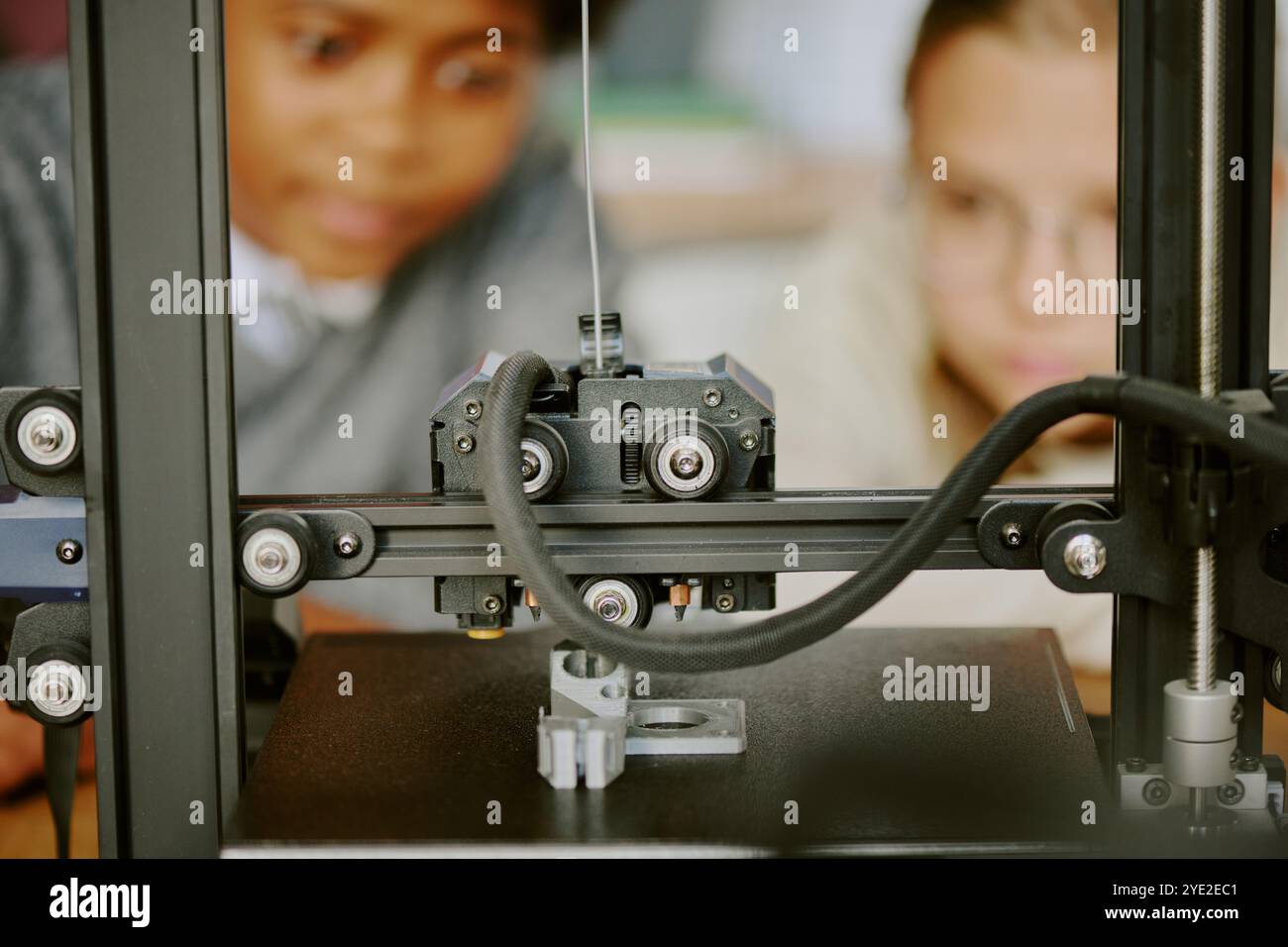 Students observing intricate 3D printing process with focused expressions, showcasing technology in educational environment Stock Photo