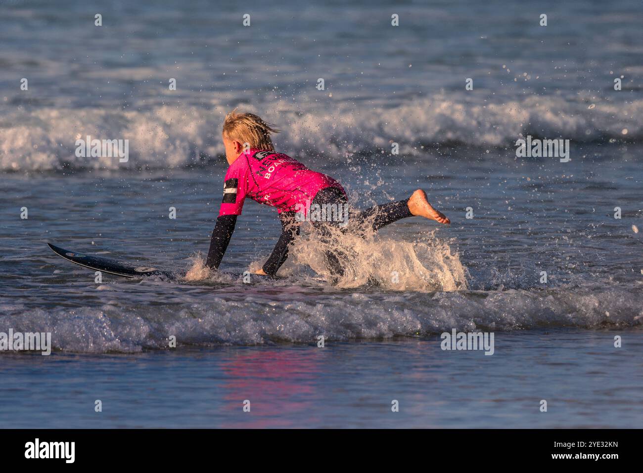 An enthusiastic young surfer from Newquay Boardriders running into the sea at Fistral in Newquay in Cornwall in the UK in Europe Stock Photo