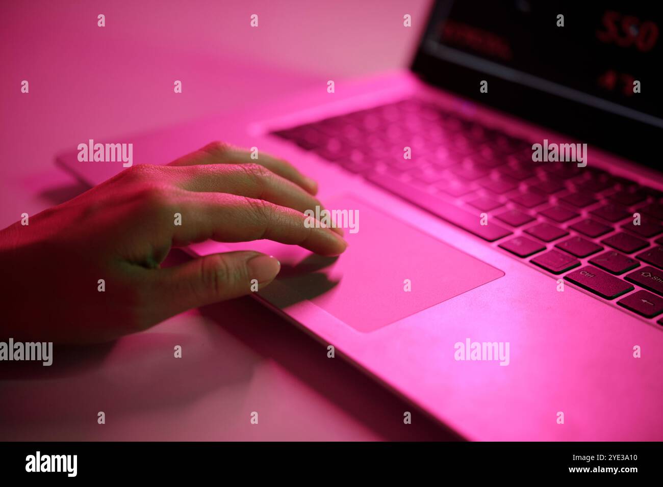 Hand Typing on Laptop with Pink Light Reflection Stock Photo