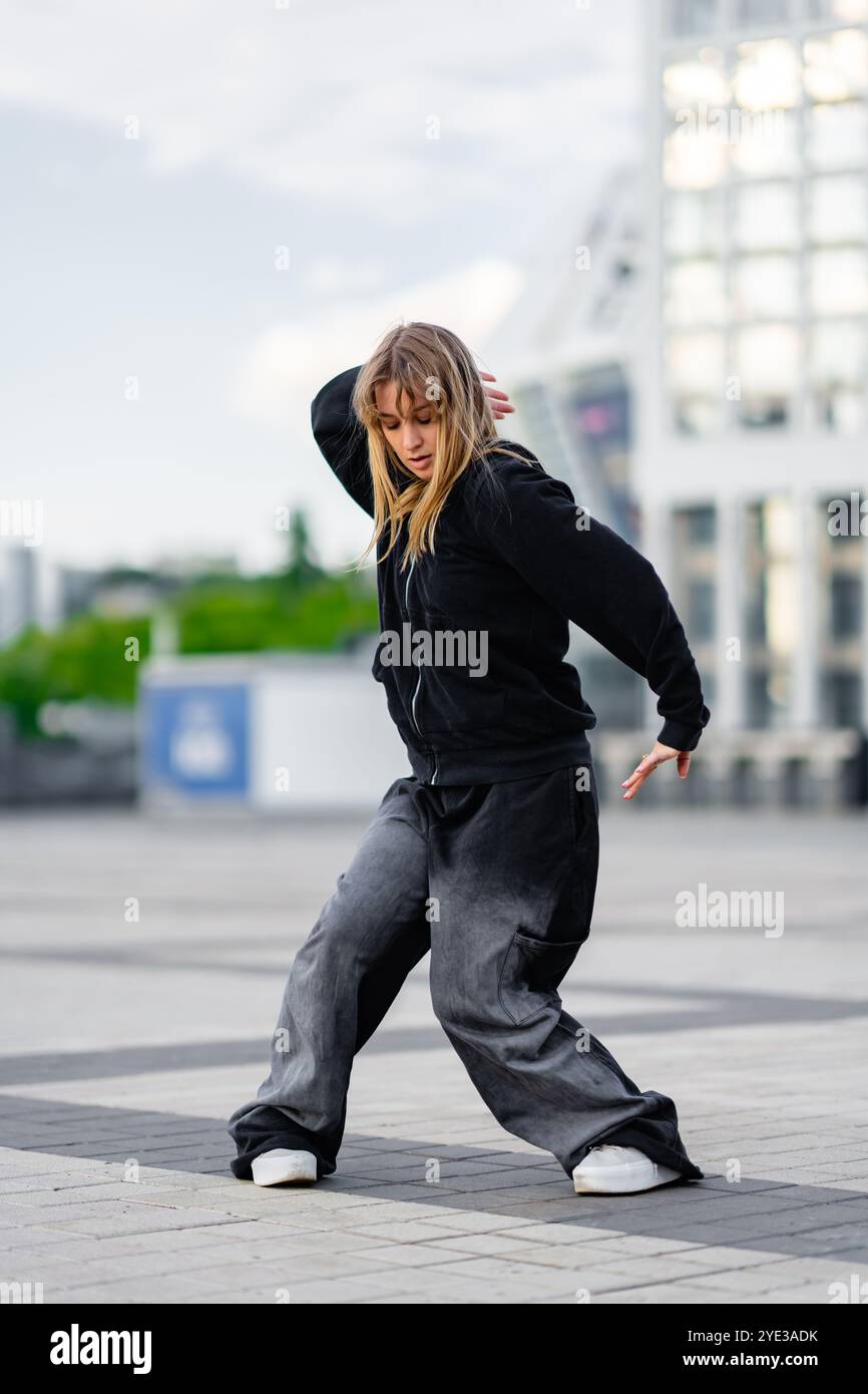 Young dancer practicing street style moves in an urban plaza setting Stock Photo