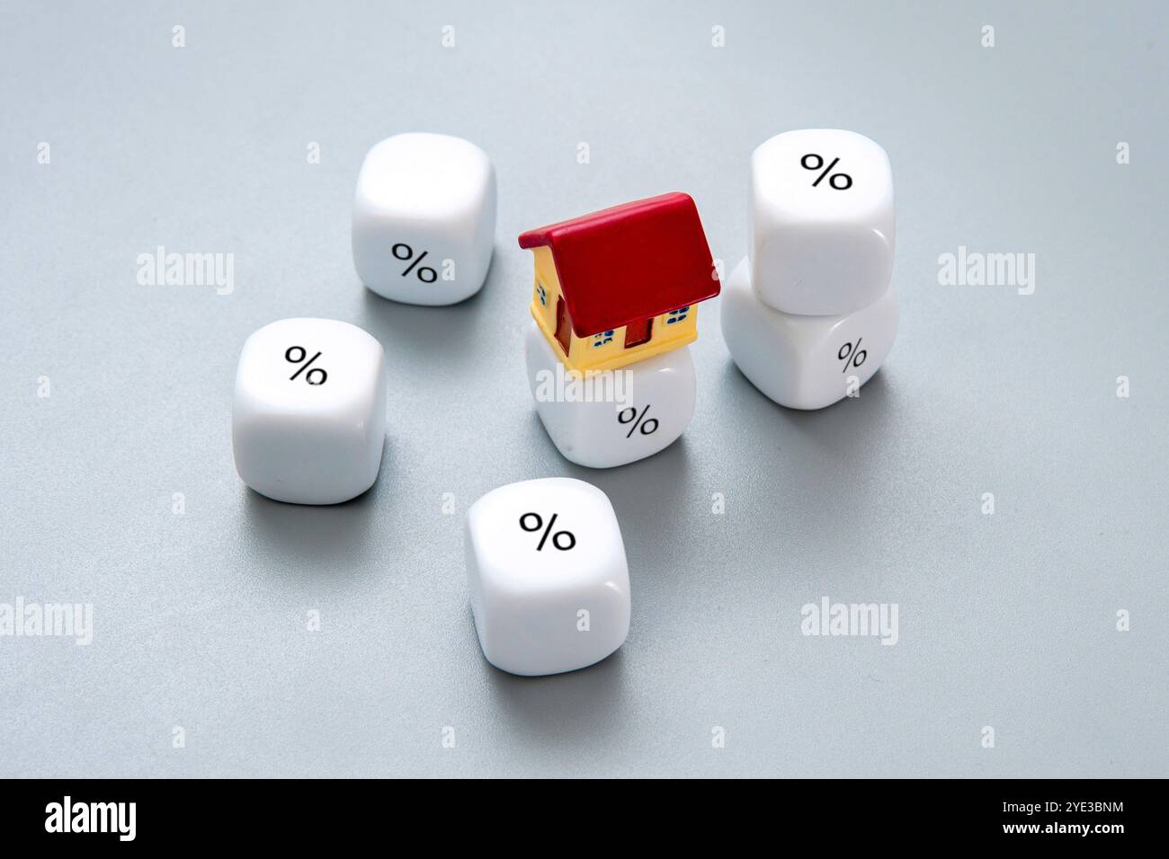 A small house surrounded by dice with percentage symbols. Property taxes, real estate costs concept. Stock Photo