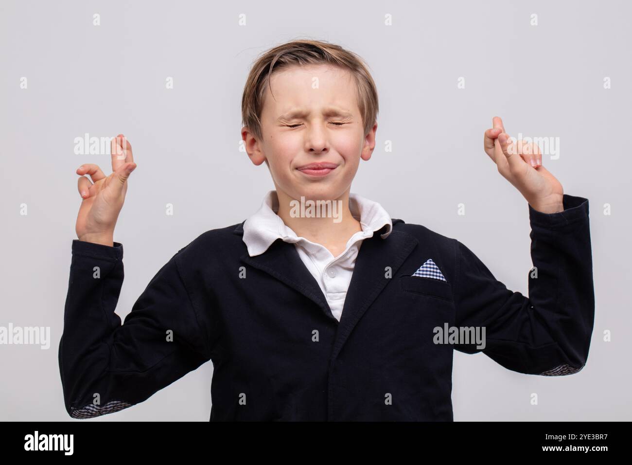 A teenage boy, a high school student, crossed his fingers so that he would not be called to the school board. A schoolboy gesture that protects agains Stock Photo