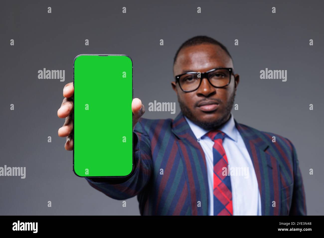 A man holding a green screen phone with a formal attire, perfect for stock footage or creative projects, space for text Stock Photo